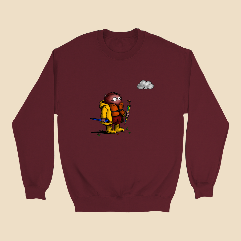 Sweatshirt featuring a cartoon creature wearing a raincoat, life jacket, and rain boots while carrying two umbrellas and staring nervously at a single cloud overhead.