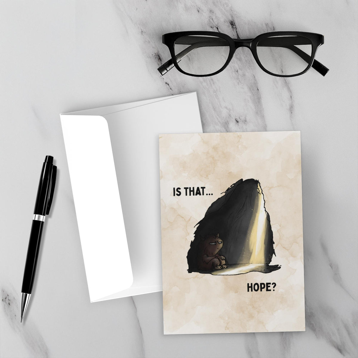 Is That Hope mental health humor greeting card featuring a tired brown monster sitting in a dark cave as a beam of warm light breaks through, with the words “Is That... Hope?”
