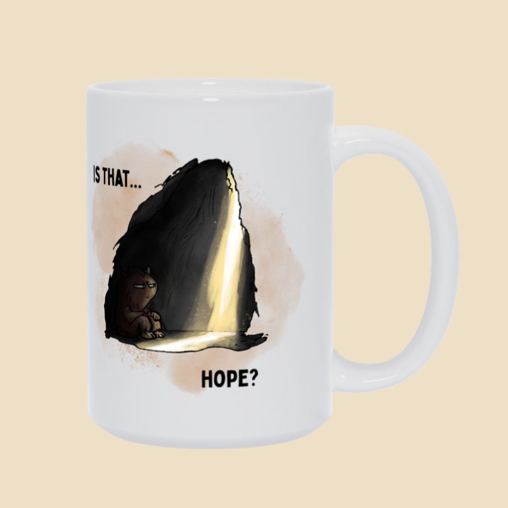 White mug featuring the “Is That… Hope?” depression humor design with a small illustrated monster sitting inside a dark cave as a beam of light shines in.