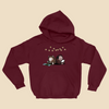 Hoodie featuring two cartoon creatures sitting back to back beneath string lights, one working on a puzzle and the other writing in a notebook.