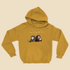 Hoodie featuring two cartoon creatures sitting back to back beneath string lights, one working on a puzzle and the other writing in a notebook.