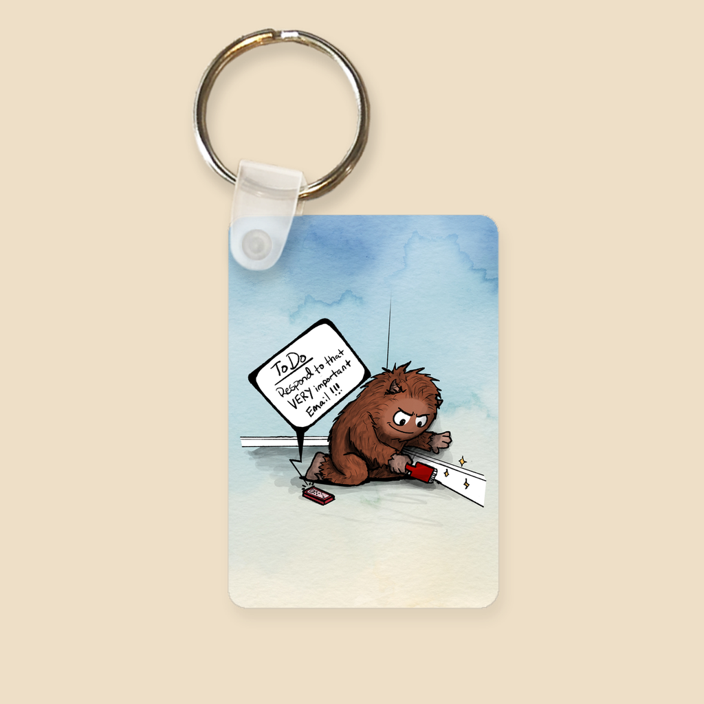 Keychain featuring a brown furry monster sitting on the floor cleaning a baseboard while a phone reminds him to respond to an important email.