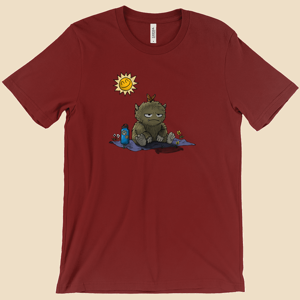 T-shirt featuring a furry monster sitting miserably in the sunshine while the cheerful world around it enjoys a beautiful day.